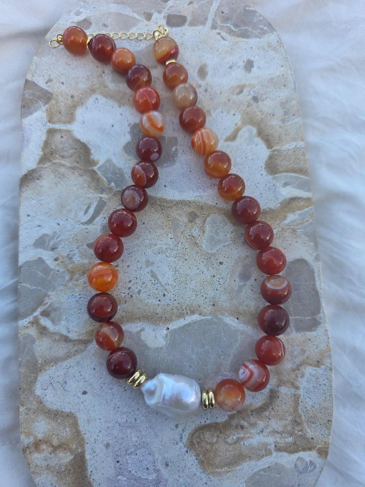 Stunning, captivating, memorising its all words that come to mind with this piece! From the large chunky 12mm Carnelian. Bold flat space beads that are stacked around your magically massive fresh water centre pearl.
With gold tarnish resistant hardware.