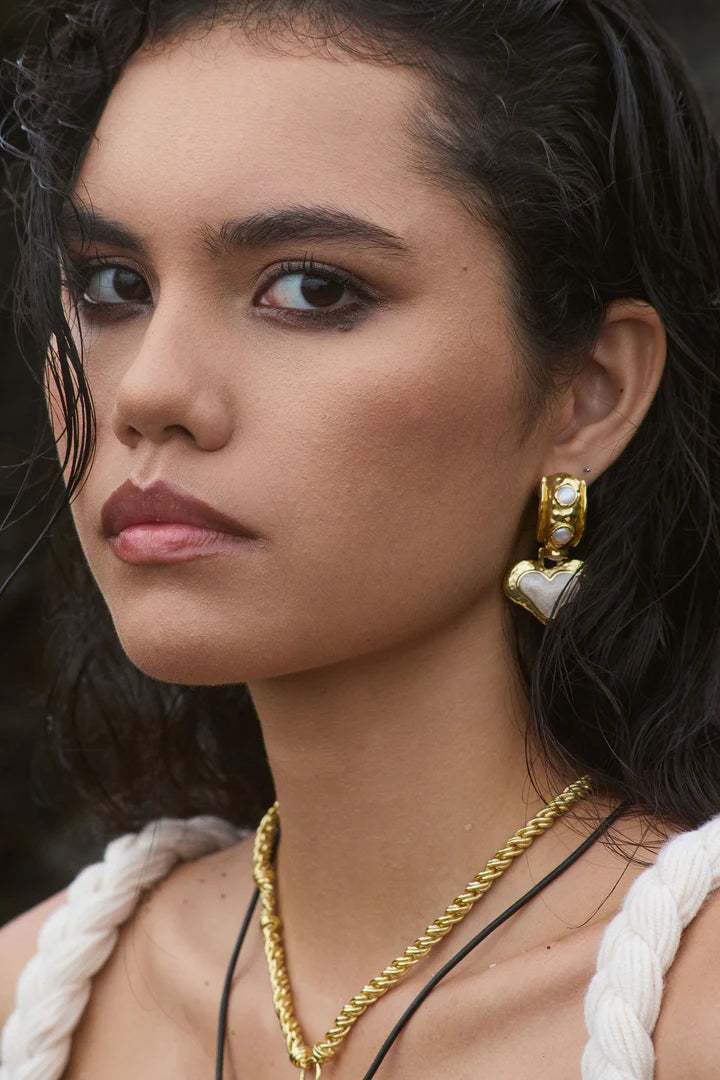 The Elena Earrings are a romantic nod to sun-soaked summers and ancient beauty, where antique ruins meet modern elegance. Featuring heart-shaped silhouettes bathed in gold, adorned with lustrous freshwater pearls and hand applied pearlescent enamel detailing.
Part of our Sirens Collection, these earrings draw from the timeless charm of the Mediterranean—where molten textures echo the ruins of antiquity, and every shimmer captures the glint of sea and sky.