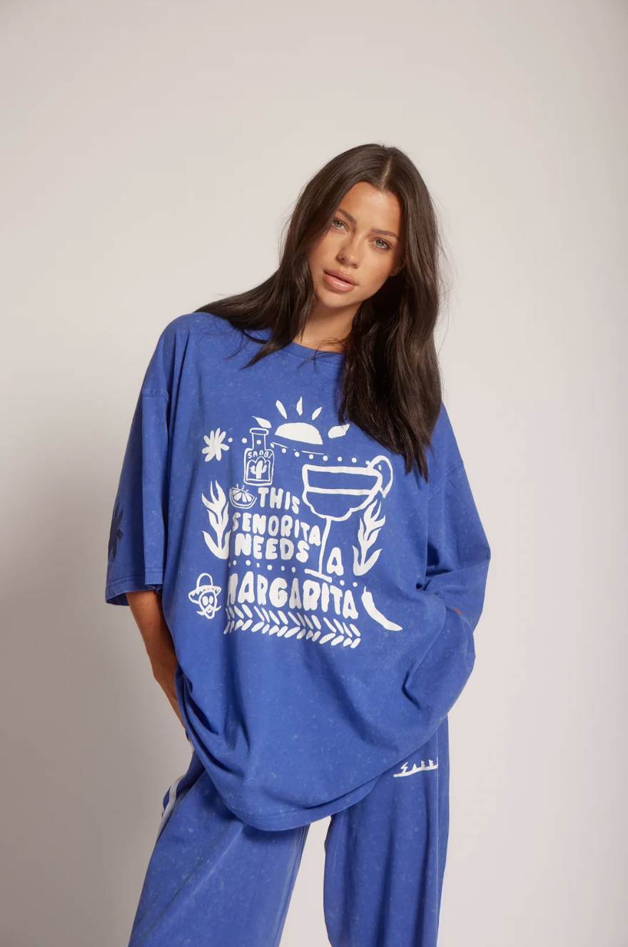 The Very Oversized Margie Tee - Royal - SABBI
The Very Oversized Margie Tee is the one you throw on when you’re absolutely not doing boring. ??
Think: sun-soaked mornings, salty hair and that first icy margarita. Cut in Sabbi’s very oversized fit, it drapes off the body with that perfectly slouchy, borrowed-from-your-bestie energy. She’s crafted from our signature soft, washed cotton that feels like you’ve already loved her for years.
The front features our hand-drawn “This Señorita Needs A Margarita”