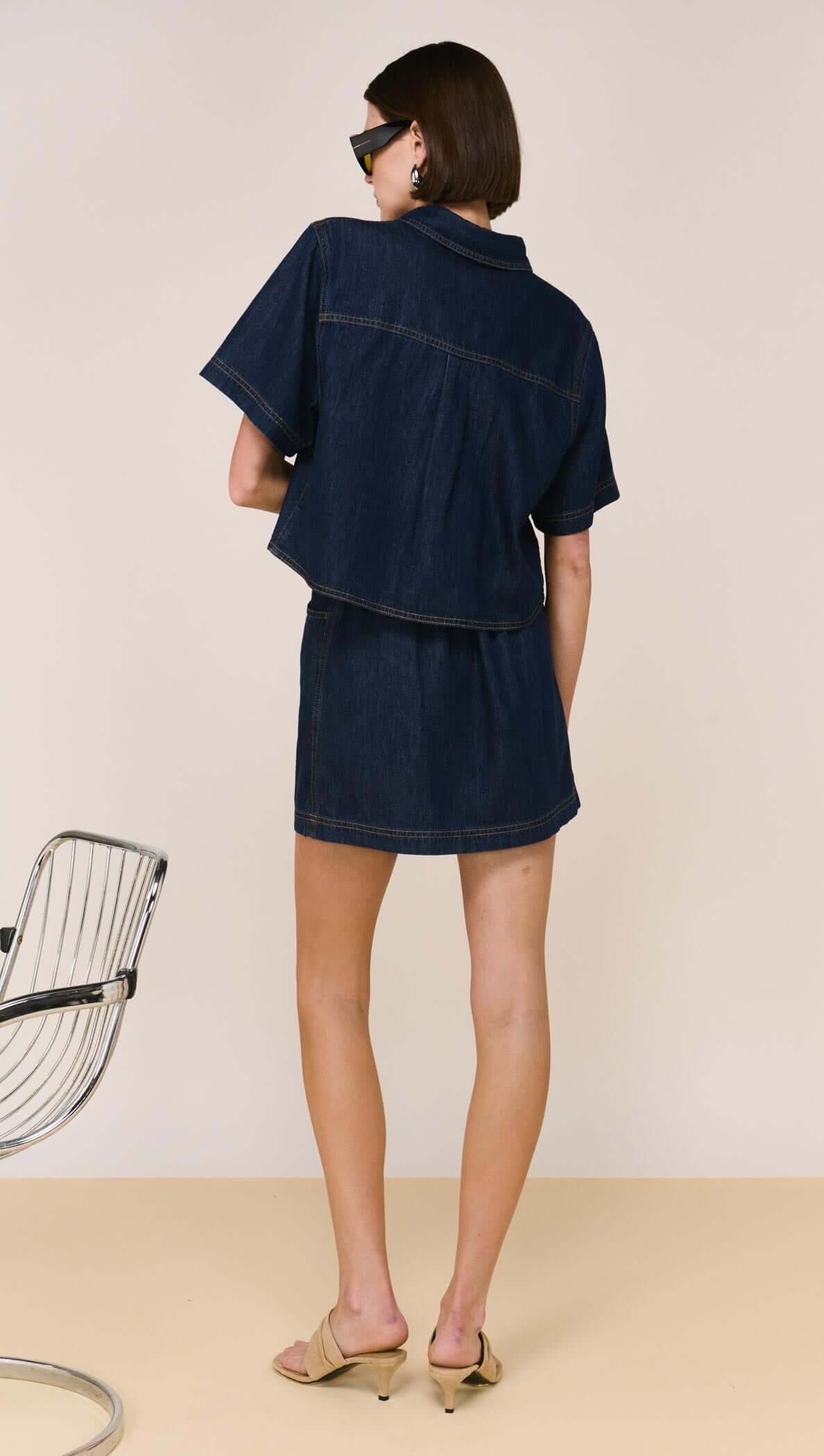 The Lea Denim Cropped Short-Sleeve Shirt is a modern take on classic denim, designed with a structured cropped silhouette and clean, tailored lines. Crafted from a soft cotton and lyocell blend, it offers a comfortable, lightweight feel while maintaining a polished finish - perfect for elevated everyday styling.