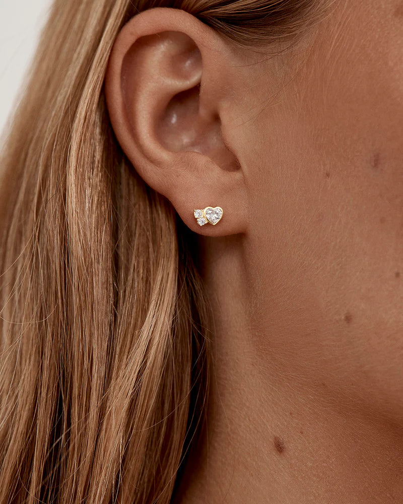 The Dream Lover Heart Stud Earrings speaks to the unspoken connections and the in-between moments of utmost intimacy. The delicate heart cluster design encapsulates the dreamy moments of tender love and connections we hold closest to our hearts.
18k Gold Vermeil: 2.5 microns of 18 carat gold coating a sterling silver base.
Features heart (bezel setting) and round (claw) cut cubic zirconias.
Sold as a pair.
Size: 7 x 5mm.
Polished finish. 