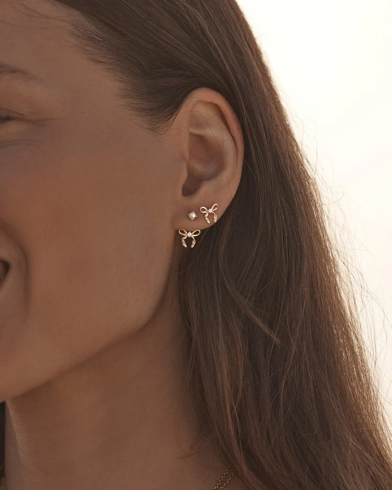 By Charlotte - The Forever More Bow Stud Earrings are a playful and delicate ode to love and romance. This keepsake is a tangible expression of the saying "tied together", with the bows symbolising love, cherished bonds, and devotion.
18k Gold Vermeil: 2.5 microns of 18 carat gold coating a sterling silver base.
Delicate bow design set with a sparkling cubic zirconia.
Sold as a pair.
9 x 8mm.
Polished finish. 