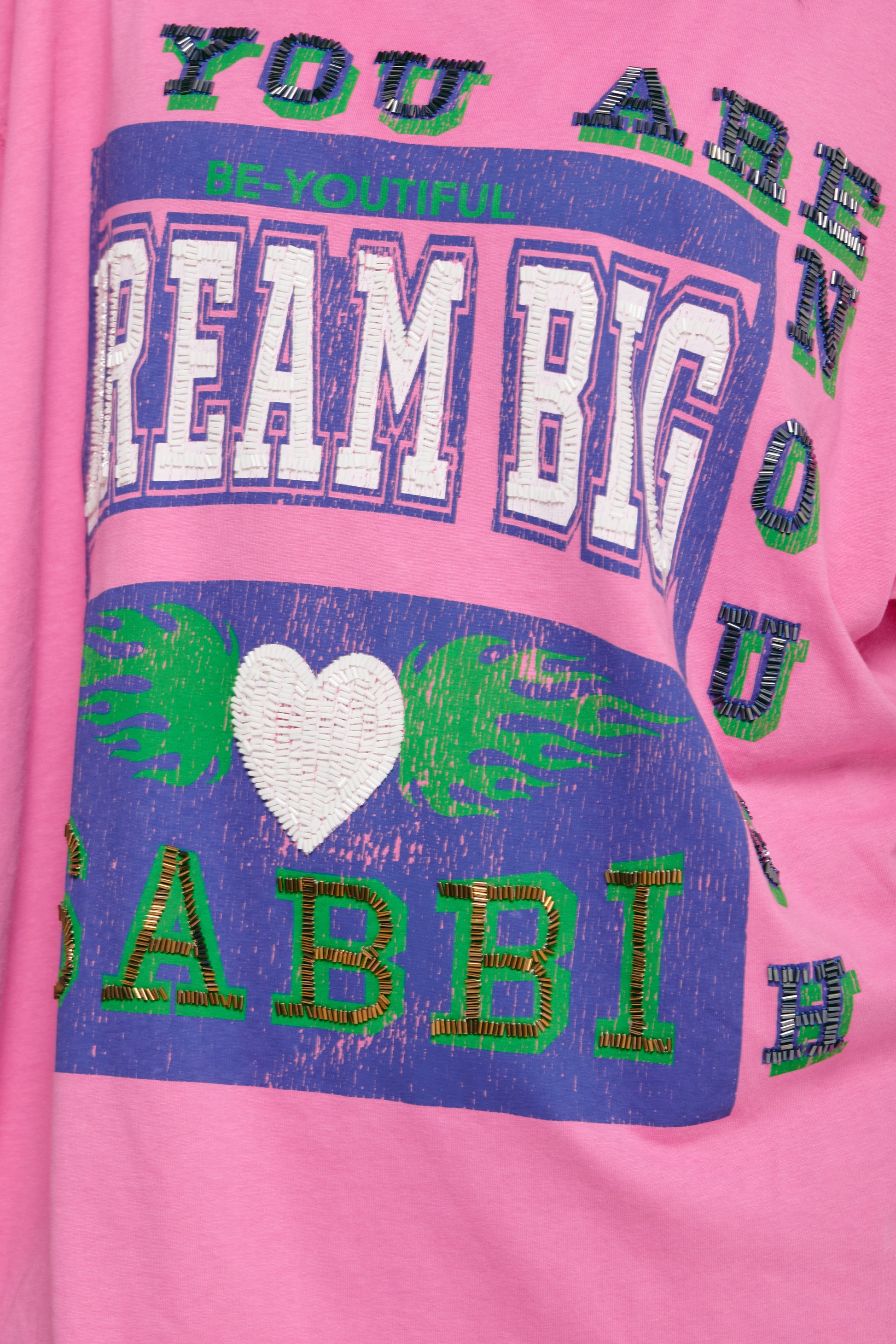 Big fit. Bigger dreams. All vibes.

The Very Oversized Dream Big Beaded Tee from Sabbi is your go-to for effortless, bold style. Made for dreamers, doers, and anyone who loves to make a statement without saying a word, this tee brings major energy in a seriously comfy, relaxed silhouette.

Sporting a varsity-inspired “Dream Big” front print with eye-catching beaded detailing, plus a fearless “Be Fearless 71” statement on the back, it’s all about vintage sports vibes with that signature Sabbi twist. Whether 