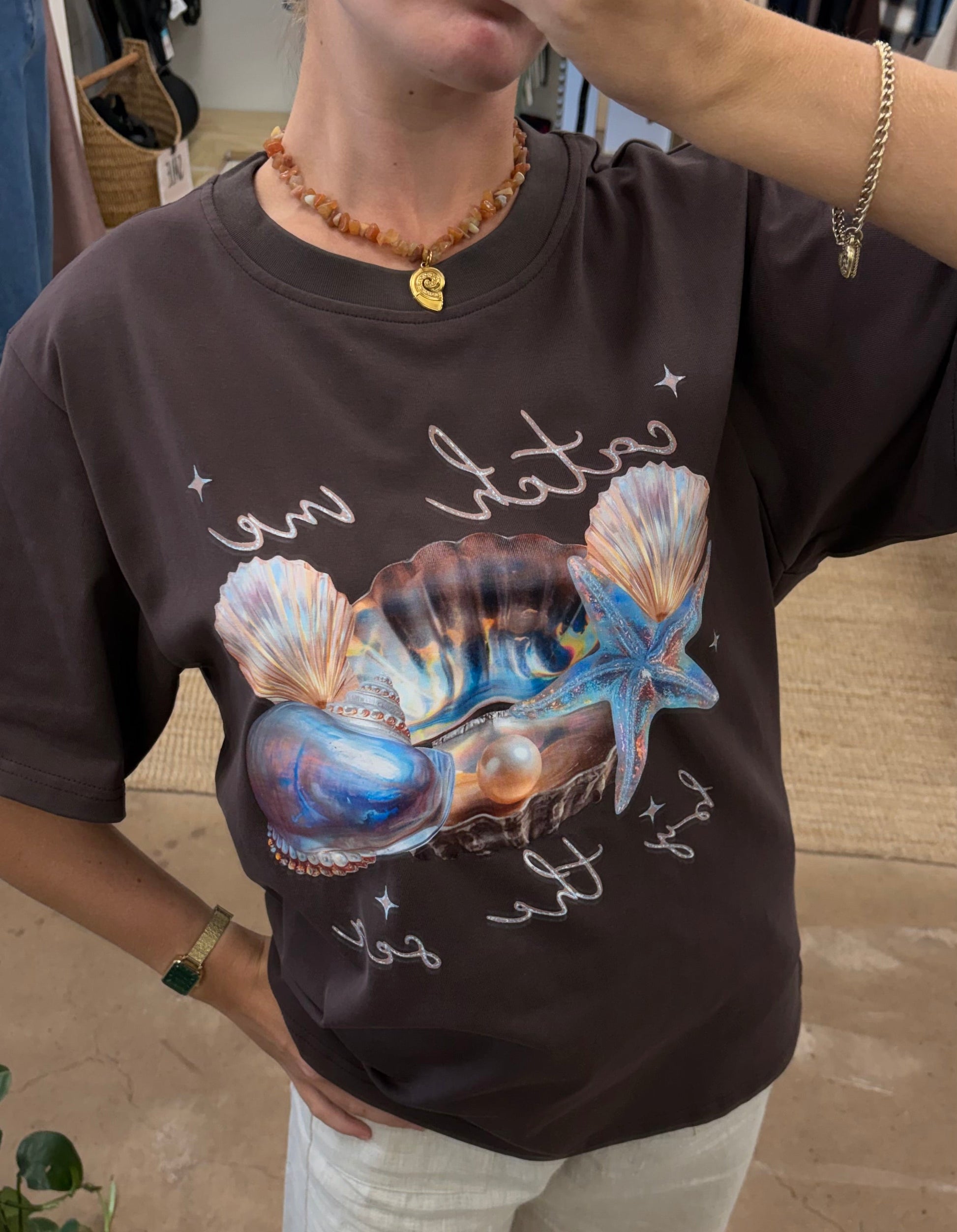 Catch Me By The Sea Tee - Paper Heart 

The Catch Me By Sea Tee features an oversized fit and a circle neck for comfort and ease of wear. Its chocolate brown fabric is complemented by a detailed sea shell chrome print, adding a distinctive visual element suitable for casual and relaxed settings.