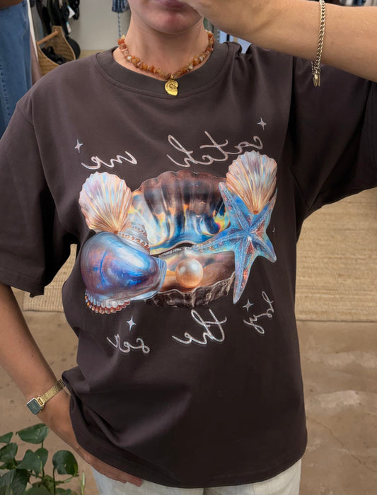 Catch Me By The Sea Tee - Paper Heart 

The Catch Me By Sea Tee features an oversized fit and a circle neck for comfort and ease of wear. Its chocolate brown fabric is complemented by a detailed sea shell chrome print, adding a distinctive visual element suitable for casual and relaxed settings.