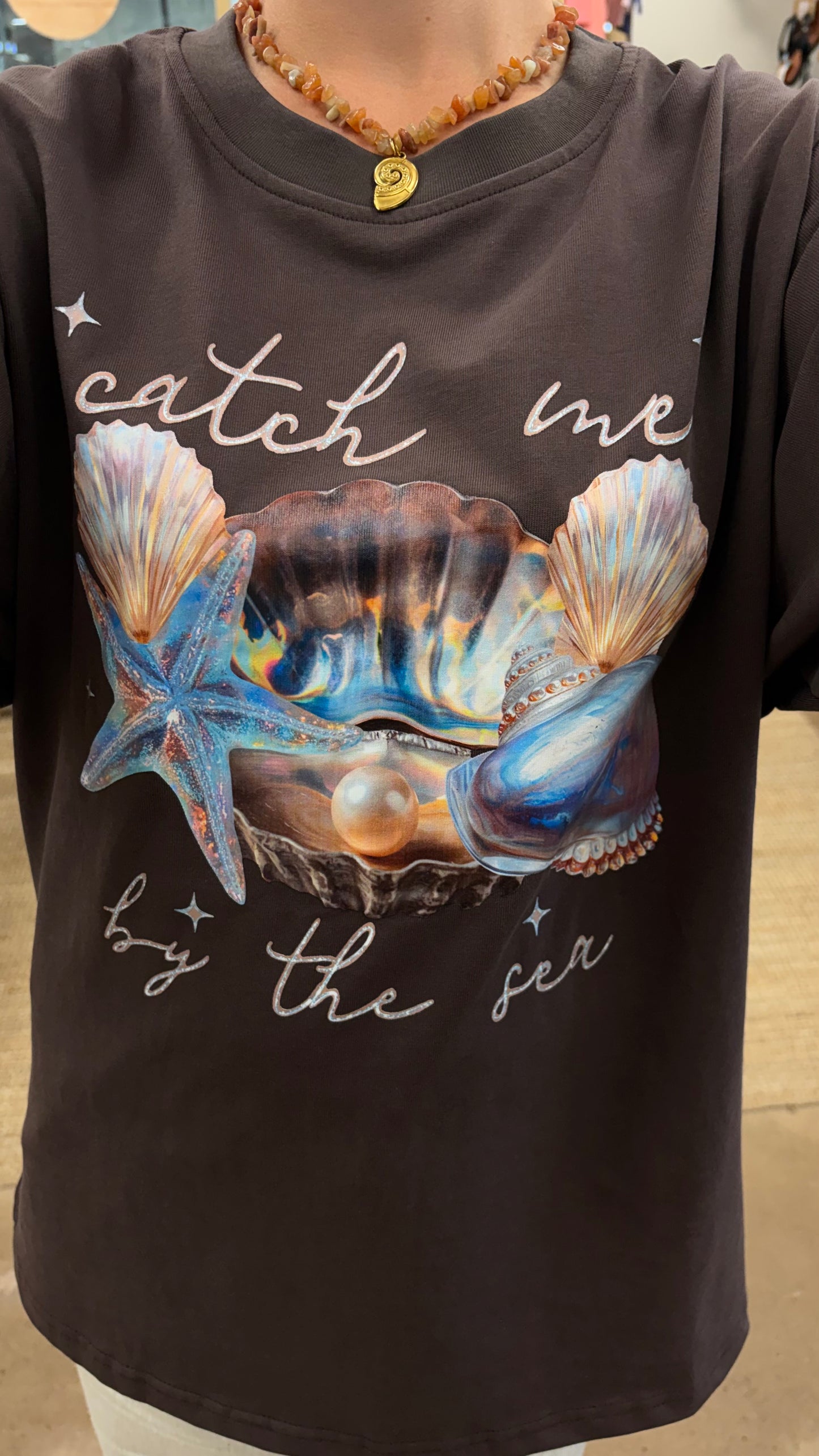 Catch Me By The Sea Tee - Paper Heart 

The Catch Me By Sea Tee features an oversized fit and a circle neck for comfort and ease of wear. Its chocolate brown fabric is complemented by a detailed sea shell chrome print, adding a distinctive visual element suitable for casual and relaxed settings.