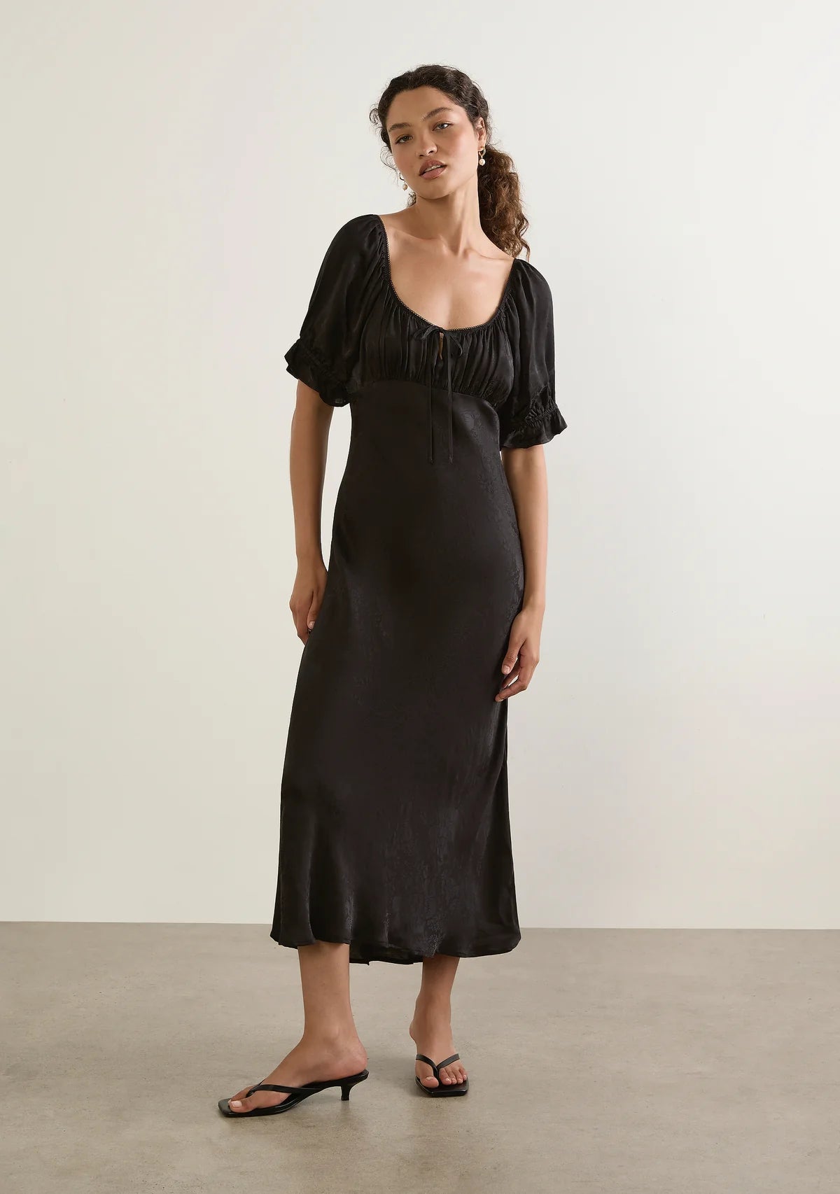 Enid Midi Dress - Auguste

The Enid Midi Dress in Black is a refined new silhouette with an effortlessly feminine feel. Featuring a soft scoop neckline with delicate trim, a gently gathered bodice, and a flattering bias-cut shape, it skims the body beautifully before falling into an elegant draped hem. Crafted in a luxurious textured floral jacquard fabrication.

Our studio model Carol is 176cm / 5'9" and wears a Size S.