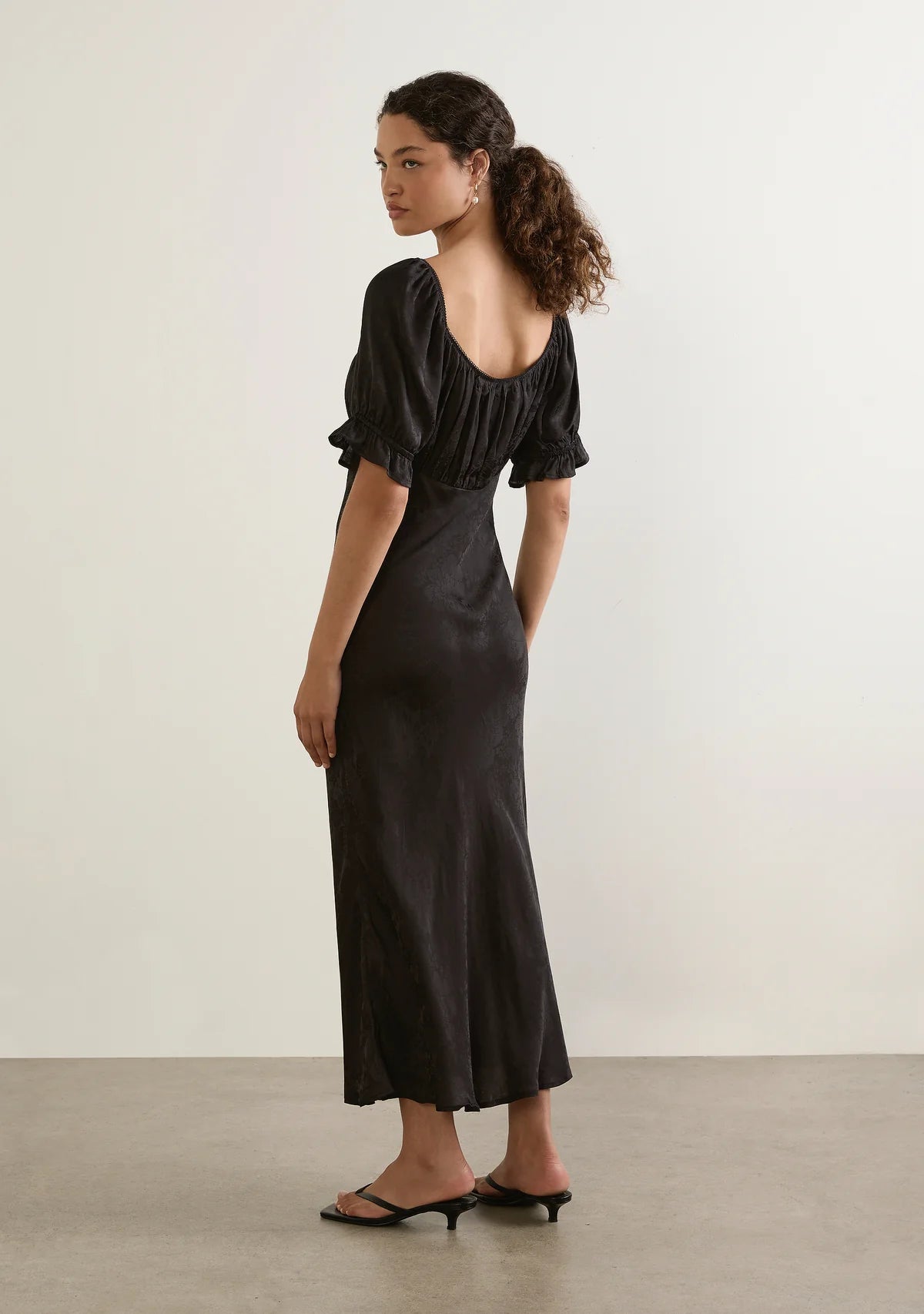 Enid Midi Dress - Auguste

The Enid Midi Dress in Black is a refined new silhouette with an effortlessly feminine feel. Featuring a soft scoop neckline with delicate trim, a gently gathered bodice, and a flattering bias-cut shape, it skims the body beautifully before falling into an elegant draped hem. Crafted in a luxurious textured floral jacquard fabrication.

Our studio model Carol is 176cm / 5'9" and wears a Size S.