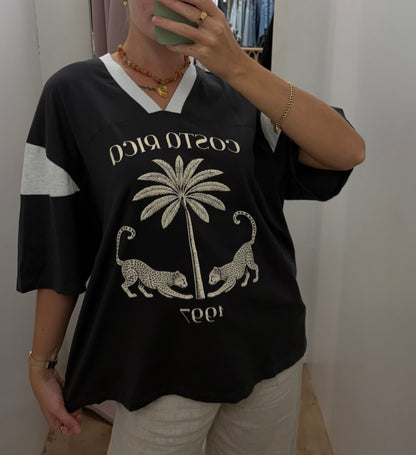 Costa Rica Tee - PaperHeart 

The Costa Rica Tee features a structured, oversized fit with a V-neckline, providing comfort and breathability. Its black-grey colorway highlights a detailed graphic print of a leopard and palm tree, reflecting Costa Rica's natural environment. The design balances style with casual versatility.