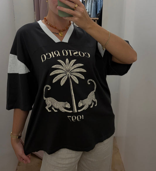 Costa Rica Tee - PaperHeart 

The Costa Rica Tee features a structured, oversized fit with a V-neckline, providing comfort and breathability. Its black-grey colorway highlights a detailed graphic print of a leopard and palm tree, reflecting Costa Rica's natural environment. The design balances style with casual versatility.