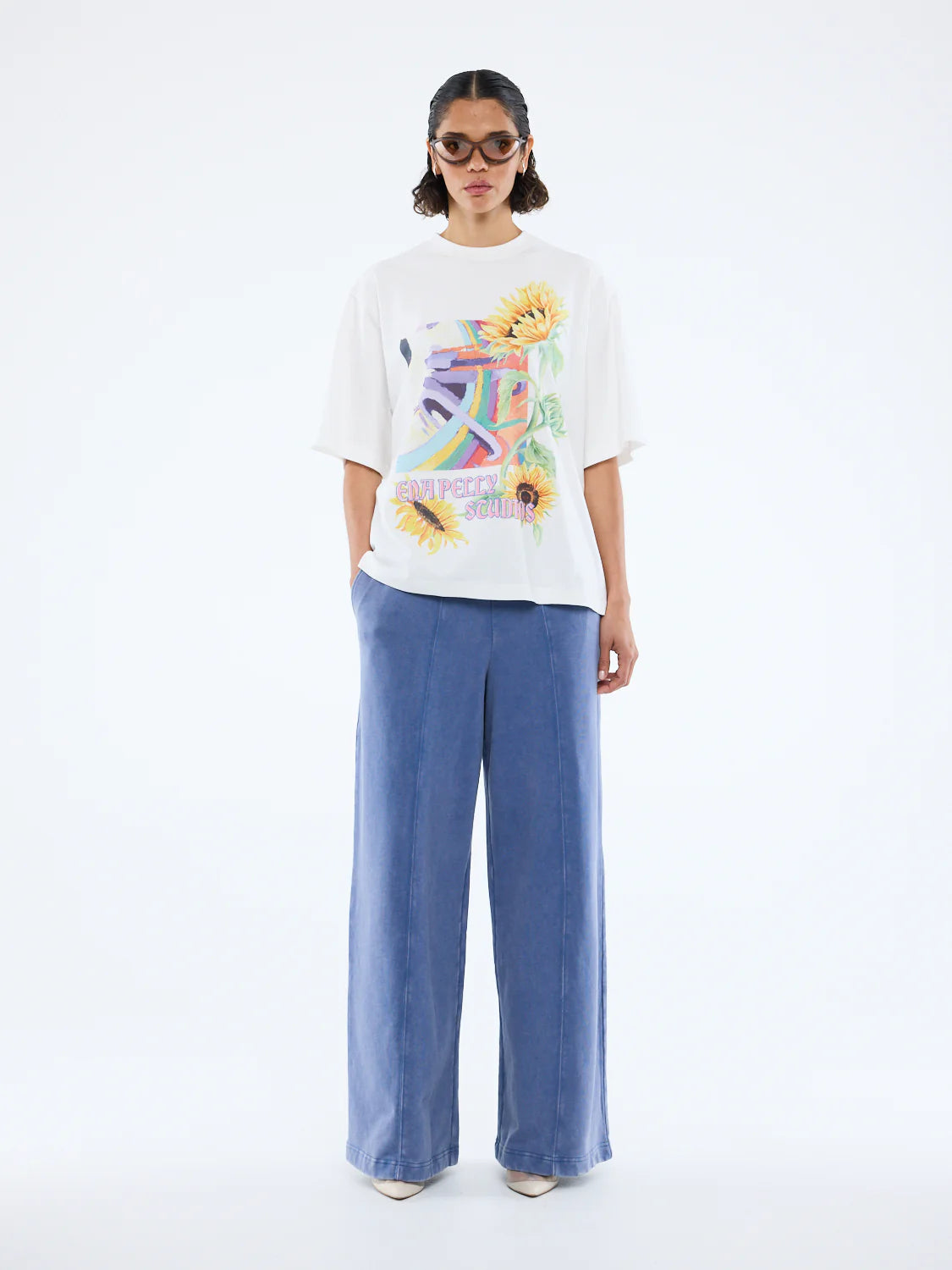 Radiant charm meets effortless style. 

The Sunflower Warp Tee by Ena Pelly is your new everyday mood-lifter. Made from soft cotton jersey, this tee offers an oversized, relaxed fit for ultimate comfort and easy layering. Its vibrant, retro-inspired warp graphic paired with bold sunflower illustrations brings nostalgic energy with a modern twist. The classic crew neckline and lived-in feel make it a go-to for weekend adventures, casual days, or layering under jackets for extra flair.