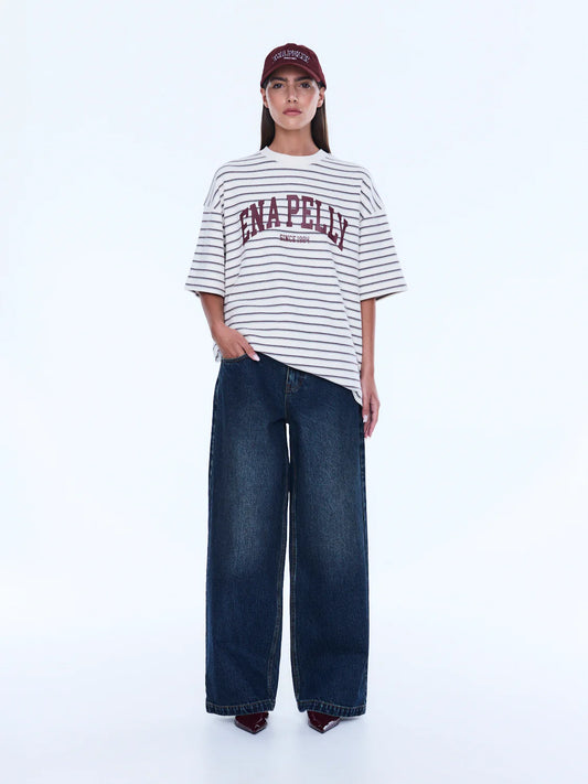 Maeve Relaxed Tee - Ena Pelly 
Everyday Cool. Effortless Edge.
The Maeve Relaxed Tee is cut in an oversized silhouette from soft cotton blend jersey with dropped shoulders and a classic crew neckline. Finished with collegiate-inspired artwork and a contrast Ena Pelly chest print that delivers bold everyday street energy.

Oversized graphic tee
Size down if you prefer a less oversized look
In house graphic artwork
Short sleeves with crew neck and drop shoulder
Model is 176cm and wears size 8
