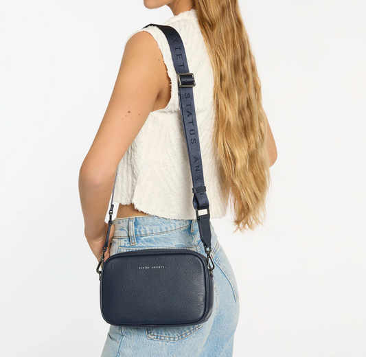 Plunder Bag With Dual Straps - Midnight Blue - Status Anxiety 
Our best selling bag of all time now comes with two different straps for twice the versatility. Clip on the leather strap for dressier occasions, or the webbed strap for a more casual vibe. It's a no brainer.

Soft shrunken pebble leather
Comes with Leather Strap Thin & Web Strap Medium
Back slider pocket
Internal zipper pocket, and open pouch pockets
Zipper close
Custom Status Anxiety lining
Comes in a Status Anxiety branded drawstring bag