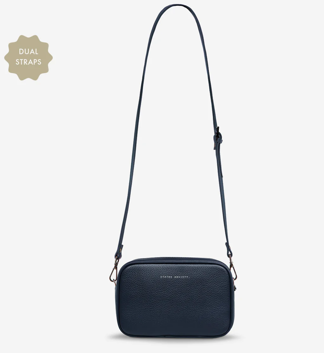 Plunder Bag With Dual Straps - Midnight Blue - Status Anxiety 
Our best selling bag of all time now comes with two different straps for twice the versatility. Clip on the leather strap for dressier occasions, or the webbed strap for a more casual vibe. It's a no brainer.

Soft shrunken pebble leather
Comes with Leather Strap Thin & Web Strap Medium
Back slider pocket
Internal zipper pocket, and open pouch pockets
Zipper close
Custom Status Anxiety lining
Comes in a Status Anxiety branded drawstring bag