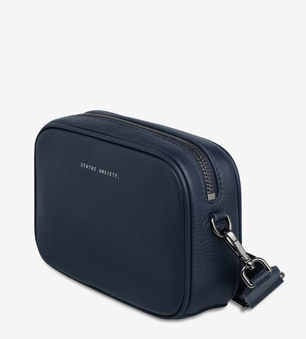 Plunder Bag With Dual Straps - Midnight Blue - Status Anxiety 
Our best selling bag of all time now comes with two different straps for twice the versatility. Clip on the leather strap for dressier occasions, or the webbed strap for a more casual vibe. It's a no brainer.

Soft shrunken pebble leather
Comes with Leather Strap Thin & Web Strap Medium
Back slider pocket
Internal zipper pocket, and open pouch pockets
Zipper close
Custom Status Anxiety lining
Comes in a Status Anxiety branded drawstring bag