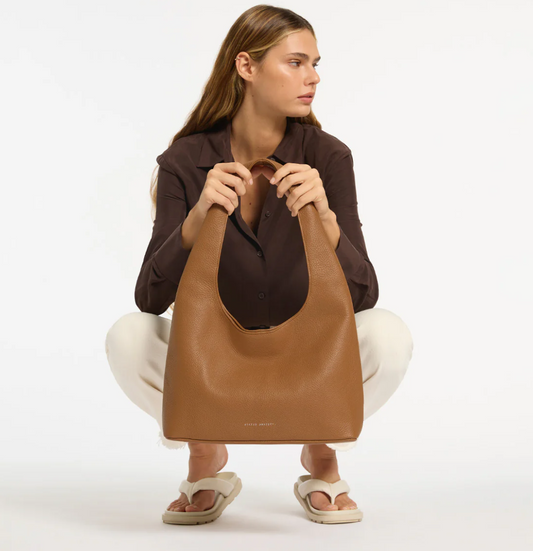 Solstice Bag - Camel - Status Anxiety 
Relaxed yet reliable, 'Solstice' is a slouchy tote that carries more than it lets on (including a 13-inch laptop). Soft, spacious, and closed with the snap of a magnet, 'Solstice' is unstructured and easygoing in all the right ways.

Soft shrunken pebble leather
Internal zipper pocket, lipstick pocket, and open pouch pocket
Fits a 13-inch laptop
Magnet closure
Custom Status Anxiety lining
Comes in a Status Anxiety branded drawstring bag
