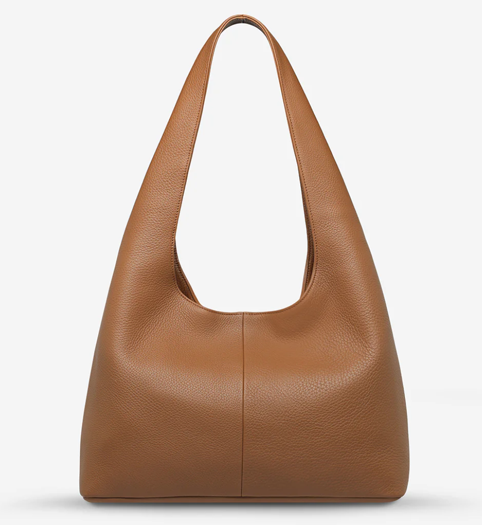 Solstice Bag - Camel - Status Anxiety 
Relaxed yet reliable, 'Solstice' is a slouchy tote that carries more than it lets on (including a 13-inch laptop). Soft, spacious, and closed with the snap of a magnet, 'Solstice' is unstructured and easygoing in all the right ways.

Soft shrunken pebble leather
Internal zipper pocket, lipstick pocket, and open pouch pocket
Fits a 13-inch laptop
Magnet closure
Custom Status Anxiety lining
Comes in a Status Anxiety branded drawstring bag