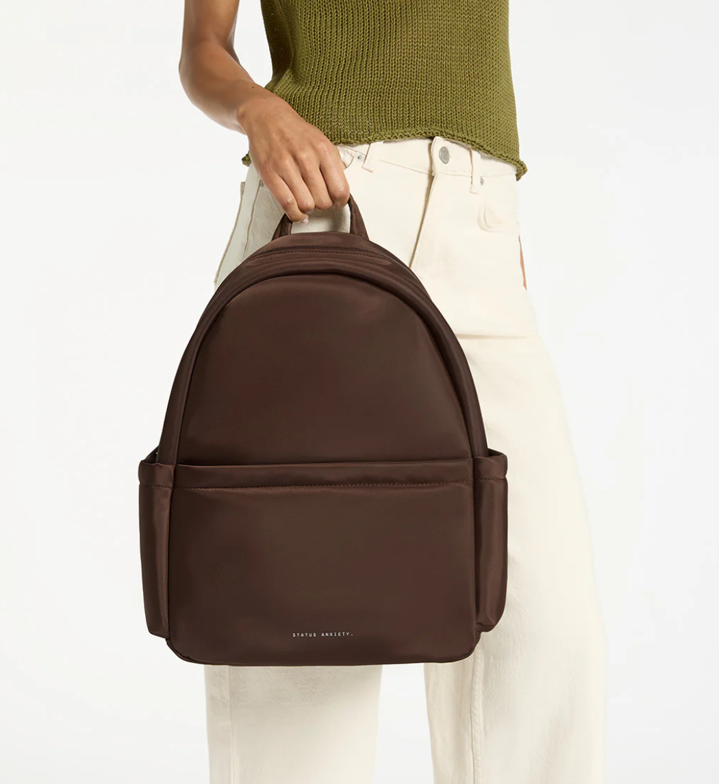 Frankie Recycled Bag - Truffle - Status Anxiety 

Tough, functional and lightweight – just what you've been looking for in a backpack (plus not to mention obvious good looks). Multiple exterior pockets keep everything within reach, while its lightweight build makes it ready for workdays, weekends, and everything between.

Premium reinforced recycled polyester (otherwise destined for landfill)
Back sleeve for sliding onto your suitcase
Dual external side pockets, and front zipper pocket
Internal open pockets