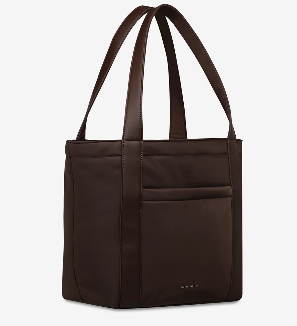 Mikah Recycled Bag - Truffle- Status Anxiety 
Structured, lightweight, and quietly capable. The 'Mikah' tote features external sleeve and zip pockets, a padded 13-inch laptop sleeve on the inside, and main compartment zip for when you want it all securely locked down. Crafted from premium reinforced recycled polyester, 'Mikah' carries light but works hard.

Premium reinforced recycled polyester (otherwise destined for landfill)
Back sleeve for sliding onto your suitcase
Front zipper pocket