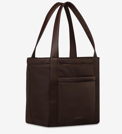 Mikah Recycled Bag - Truffle- Status Anxiety 
Structured, lightweight, and quietly capable. The 'Mikah' tote features external sleeve and zip pockets, a padded 13-inch laptop sleeve on the inside, and main compartment zip for when you want it all securely locked down. Crafted from premium reinforced recycled polyester, 'Mikah' carries light but works hard.

Premium reinforced recycled polyester (otherwise destined for landfill)
Back sleeve for sliding onto your suitcase
Front zipper pocket