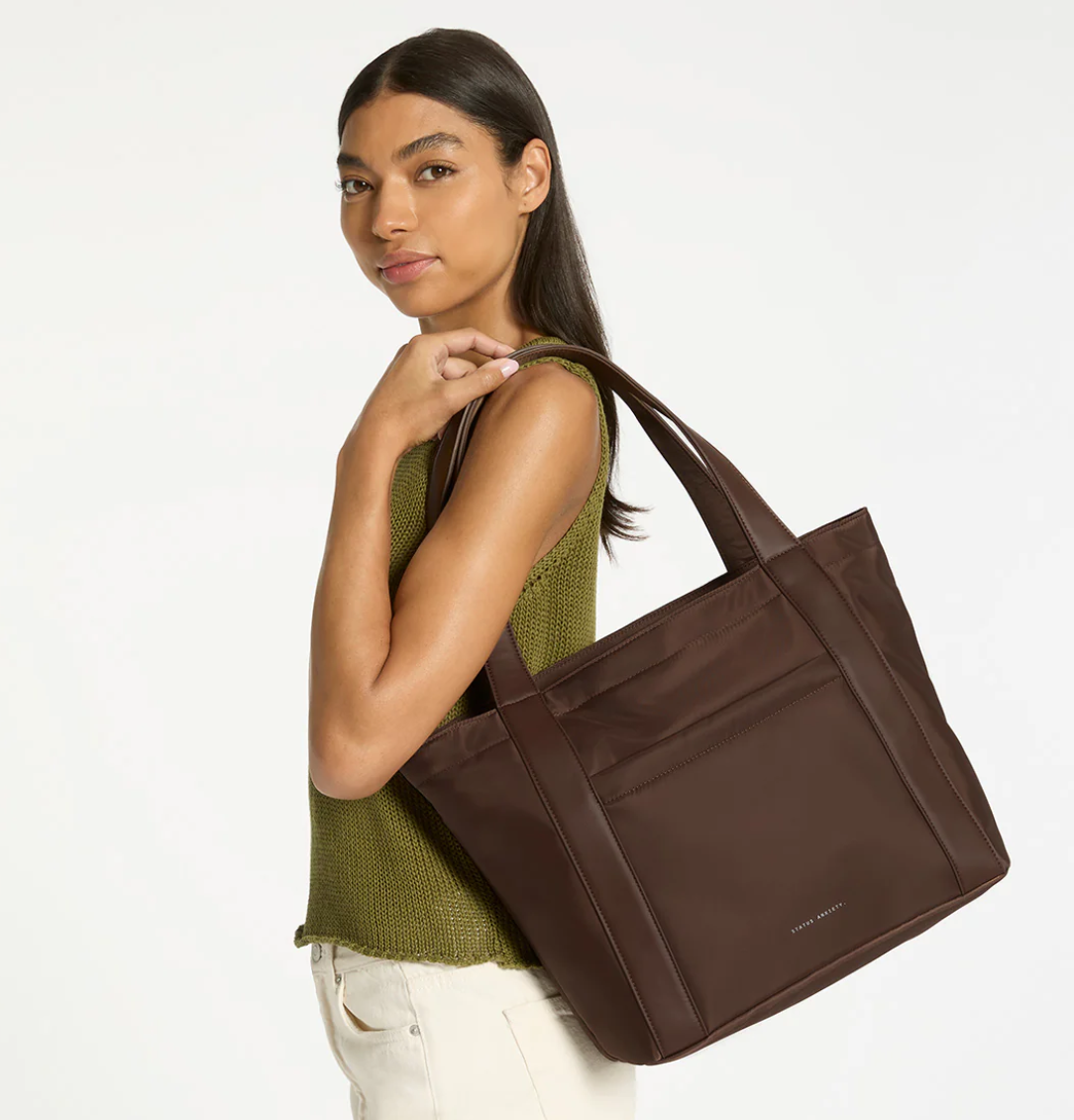 Mikah Recycled Bag - Truffle- Status Anxiety 
Structured, lightweight, and quietly capable. The 'Mikah' tote features external sleeve and zip pockets, a padded 13-inch laptop sleeve on the inside, and main compartment zip for when you want it all securely locked down. Crafted from premium reinforced recycled polyester, 'Mikah' carries light but works hard.

Premium reinforced recycled polyester (otherwise destined for landfill)
Back sleeve for sliding onto your suitcase
Front zipper pocket