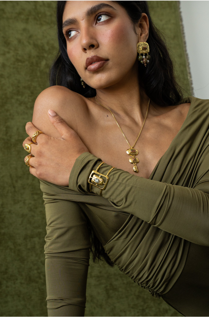 Astrid Gold Cuff - Mountain & Moon 

Description

Astrid commands attention without asking for it. A wide hammered gold cuff with an open rectangular frame at its centre, set with a Dalmatian Jasper stone - architectural, organic, and unmistakably considered.

A statement piece from the Odyssey collection - for the woman who adorns herself with meaning, not just habit.

Micron 18K gold & sterling silver plating 
to premium jewellery standards