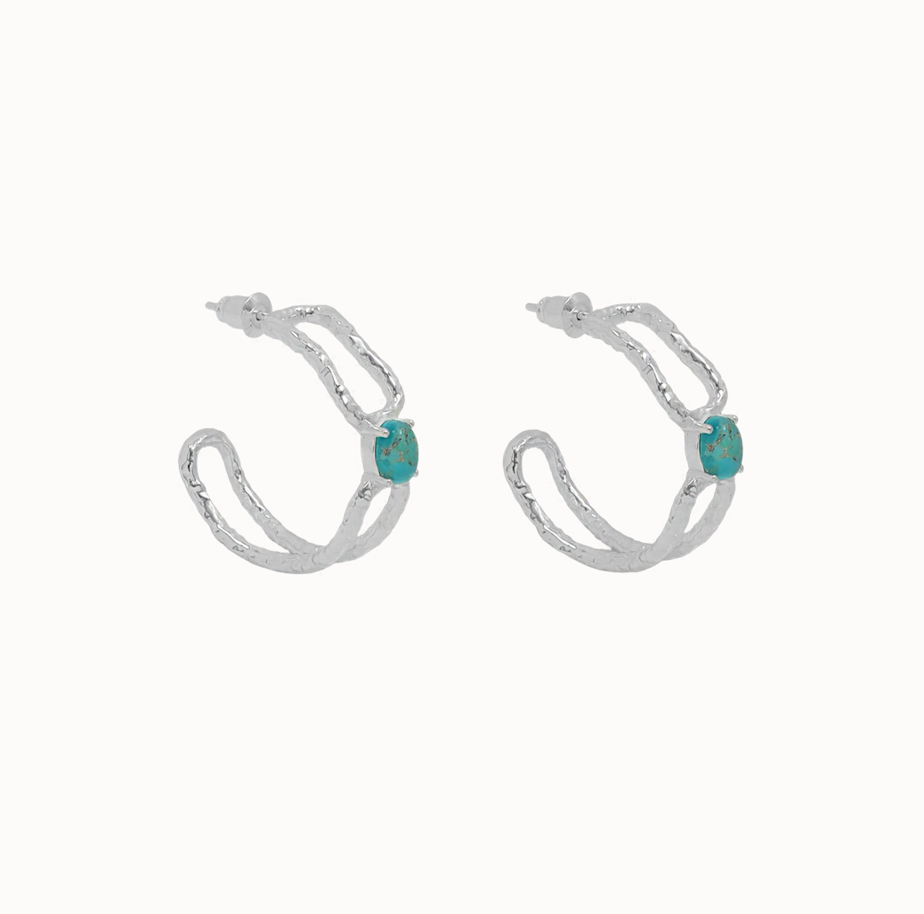 Sascha Earrings Silver - Mountain & Moon 

Description

ELEVATED ESSENTIALS • WEAR ON REPEAT

The Sascha Earrings bring sculptural sophistication to your everyday rotation. 
An organic, open double-hoop silhouette anchored by a vibrant Blue Mojave Turquoise gemstone at its centre - an unexpected focal point that feels both grounded and playful. Softly textured silver catches the light, adding dimension and a subtle vintage-inspired edge.