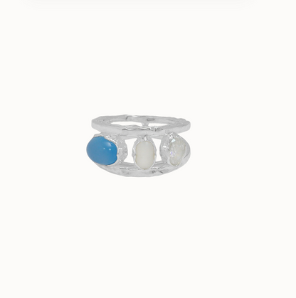 LAYERED STYLE • MODERN KEEPSAKE

Maral in silver feels lighter, cooler, and quietly striking. Two slender hammered bands frame three distinct stones — freshwater pearl, blue chalcedony, and white CZ — each set in organic bezels that give the piece an imperfect, lived-in beauty.

There’s a tension between delicacy and strength here. The double band creates structure, while the stones bring softness and light. It reflects the instinctive, material-led approach behind the Dominique Elissa x Mountain & Moon 