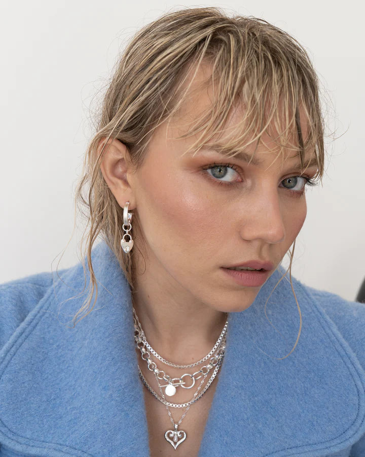 Our beloved Heart Mini Hoops, now in silver, are a perfect addition to any outfit. Whether worn with our&nbsp;gorgeous heart locket charms or solo, yes the charms are removable! These mini&nbsp;silver hoops are&nbsp;such a cute &amp; eye-catching accessory.&nbsp;Maybe you're running errands, attending a special event, or exercising, these&nbsp;small but mighty earrings are a perfect complement to your look. They're your go-to everyday earring that are never boring.&nbsp;