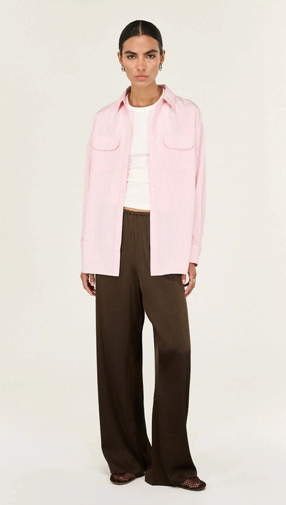 The Lina Pink Pinstriped Shirt is a modern wardrobe essential designed with a relaxed silhouette and timeless shirting details for effortless everyday wear. Crafted from a lightweight woven fabrication, it features a classic collar, button-through front and soft vertical stripe pattern for a polished yet easy finish.

- Classic collar neckline
- Button-through front closure
- Relaxed, longline silhouette
- Dual front patch pockets
- Soft pink with fine stripe detailing
- Lightweight, breathable feel
- Desig