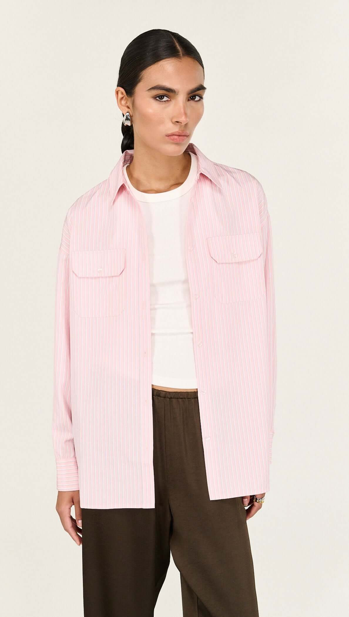 The Lina Pink Pinstriped Shirt is a modern wardrobe essential designed with a relaxed silhouette and timeless shirting details for effortless everyday wear. Crafted from a lightweight woven fabrication, it features a classic collar, button-through front and soft vertical stripe pattern for a polished yet easy finish.

- Classic collar neckline
- Button-through front closure
- Relaxed, longline silhouette
- Dual front patch pockets
- Soft pink with fine stripe detailing
- Lightweight, breathable feel
- Desig