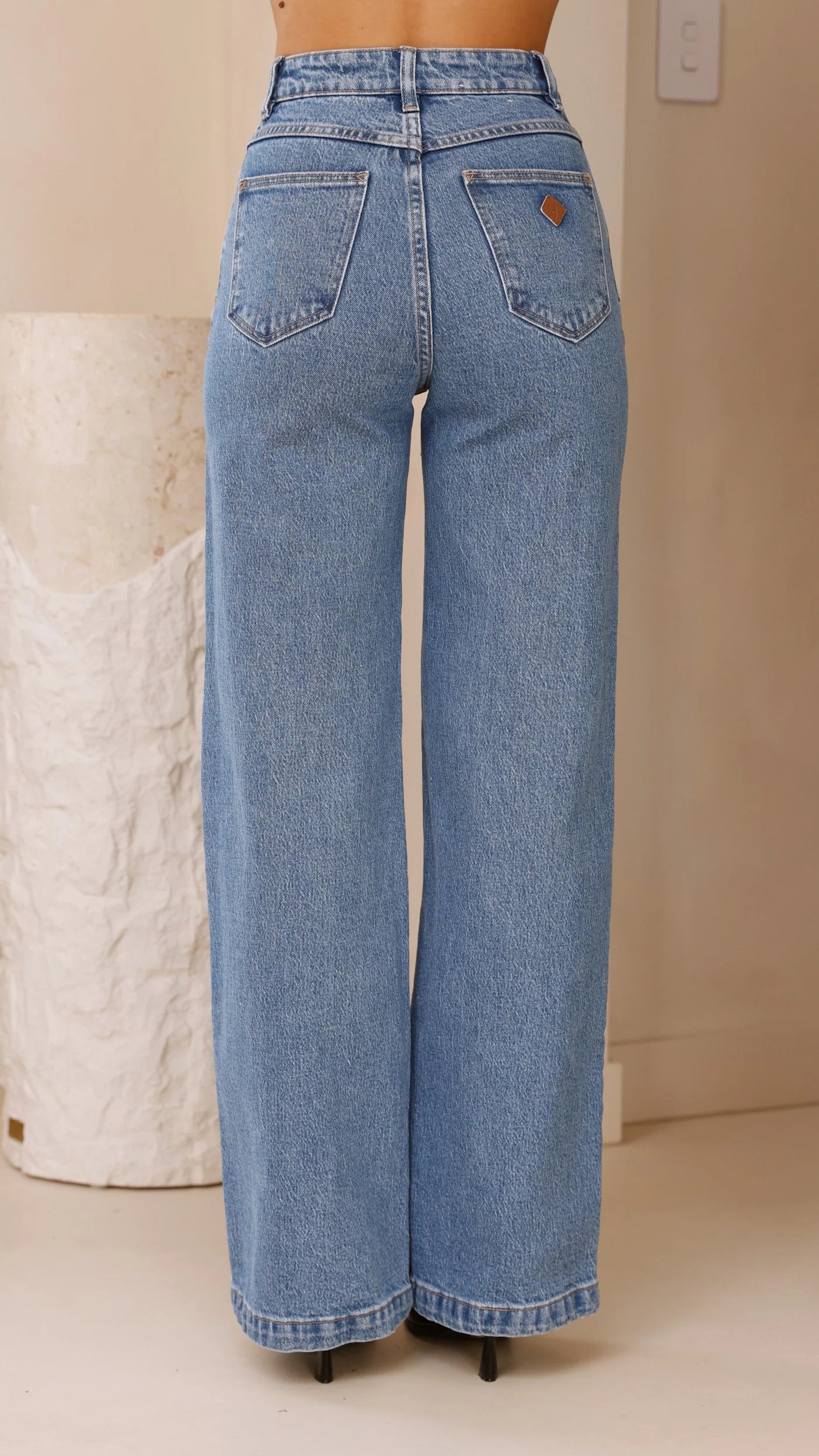 The Abrand 94 High & Wide Jeans feature a slim, fitted topblock that flatters the seat, paired with a wider leg for effortless movement. Signature details include the iconic Abrand dice logo on the back pocket in tan, bright wheat stitching, and rose gold trims that add a touch of sophistication. The zip closure ensures a secure fit.